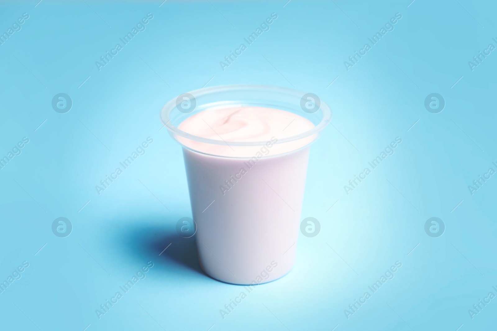 Photo of Plastic cup with creamy yogurt on color background