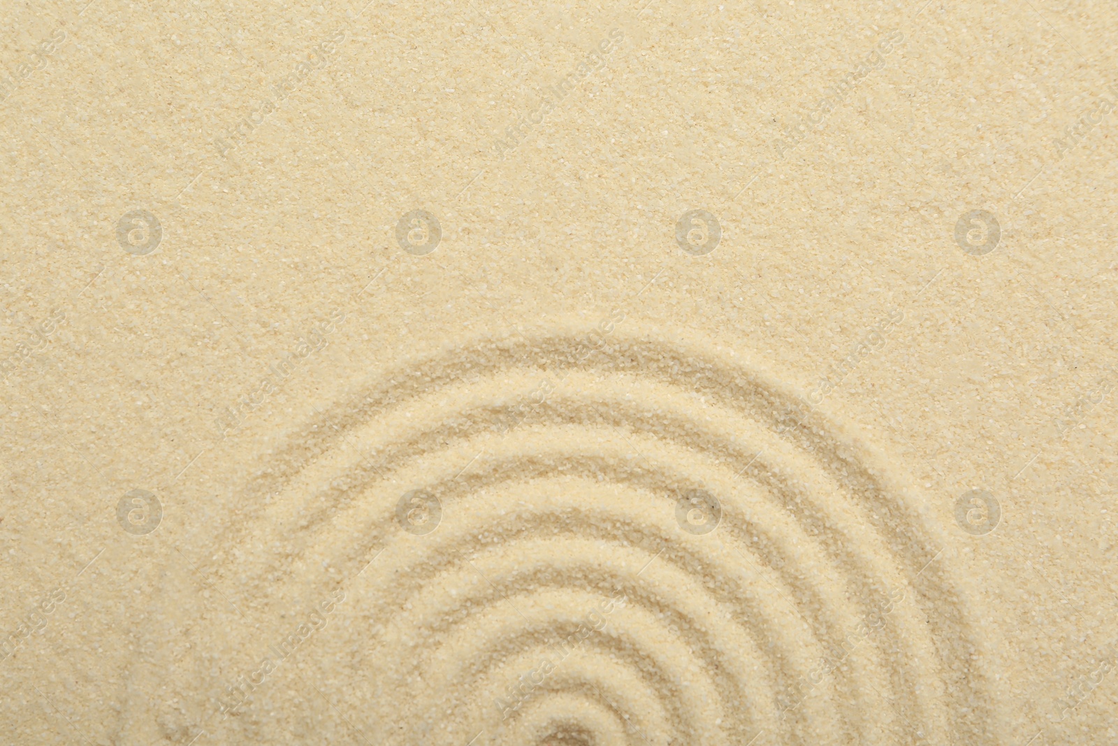 Photo of Zen rock garden. Circle pattern on beige sand