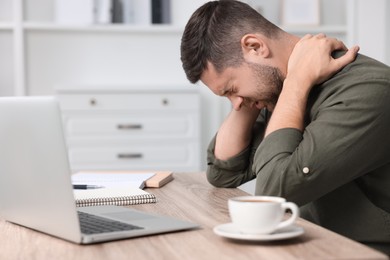 Photo of Man suffering from neck pain in office