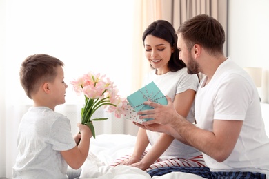 Father and son congratulating mom in bedroom. Happy Mother's Day