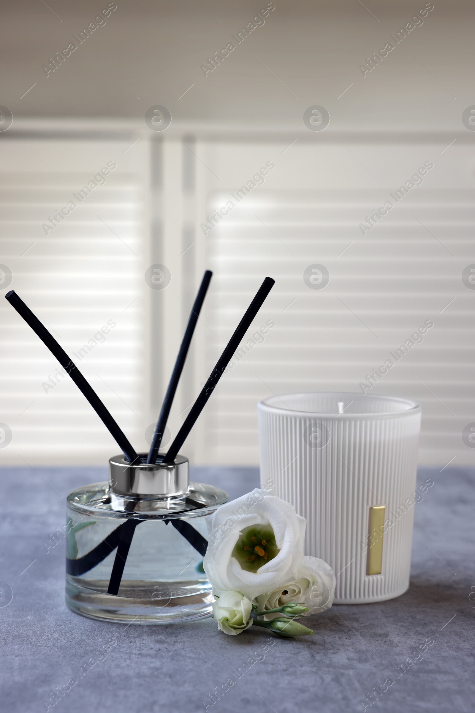 Photo of Reed diffuser, scented candle and eustoma flowers on gray marble table