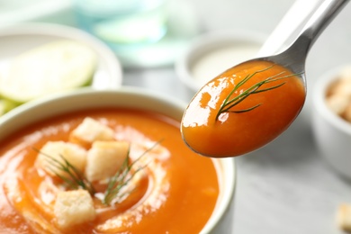 Spoon with tasty sweet potato soup over table, closeup. Space for text