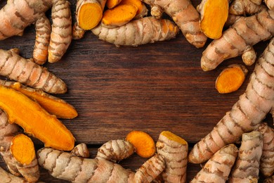 Frame made of many fresh turmeric roots on wooden table, flat lay. Space for text