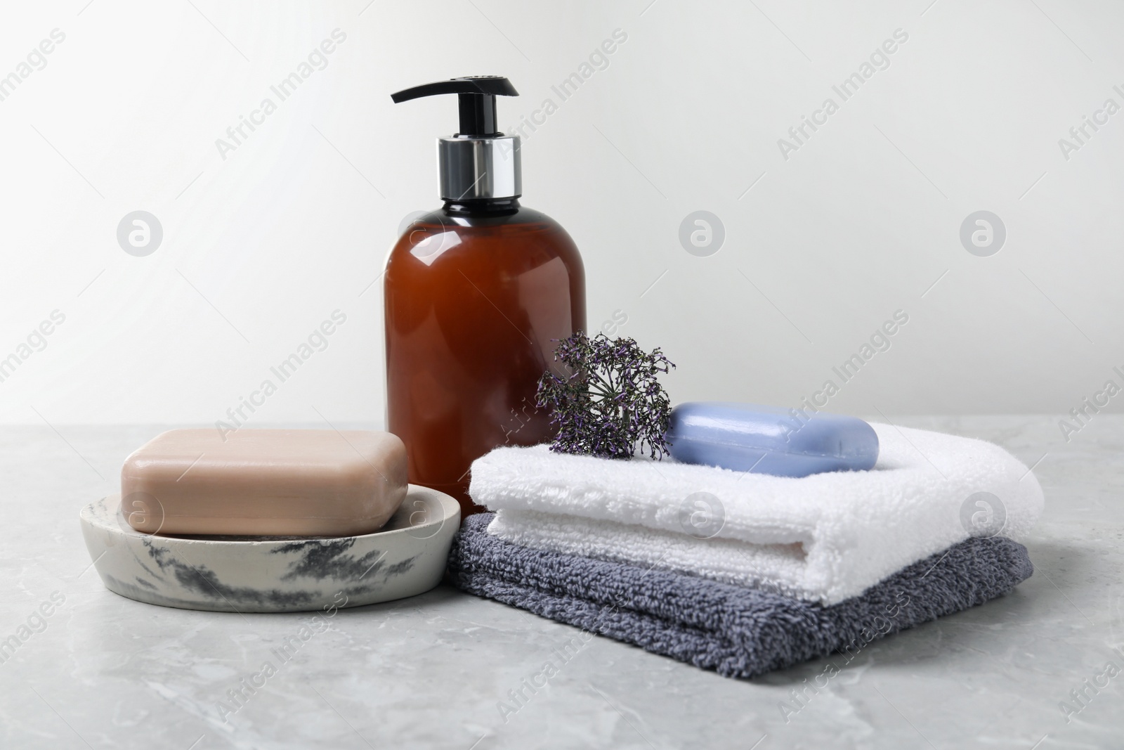 Photo of Soap bars, dispenser and terry towels on light grey table