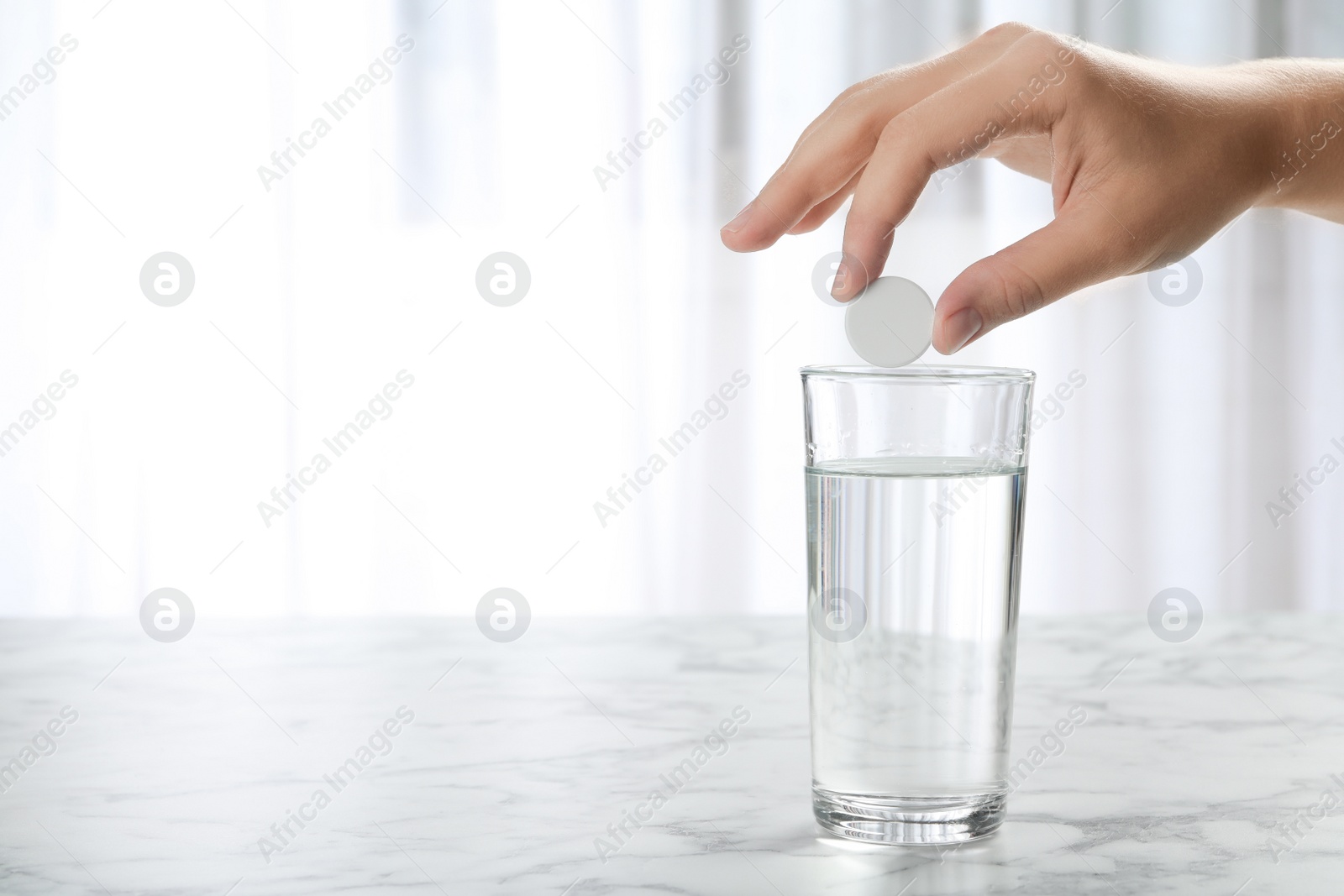 Photo of Woman putting tablet into glass of water indoors, space for text