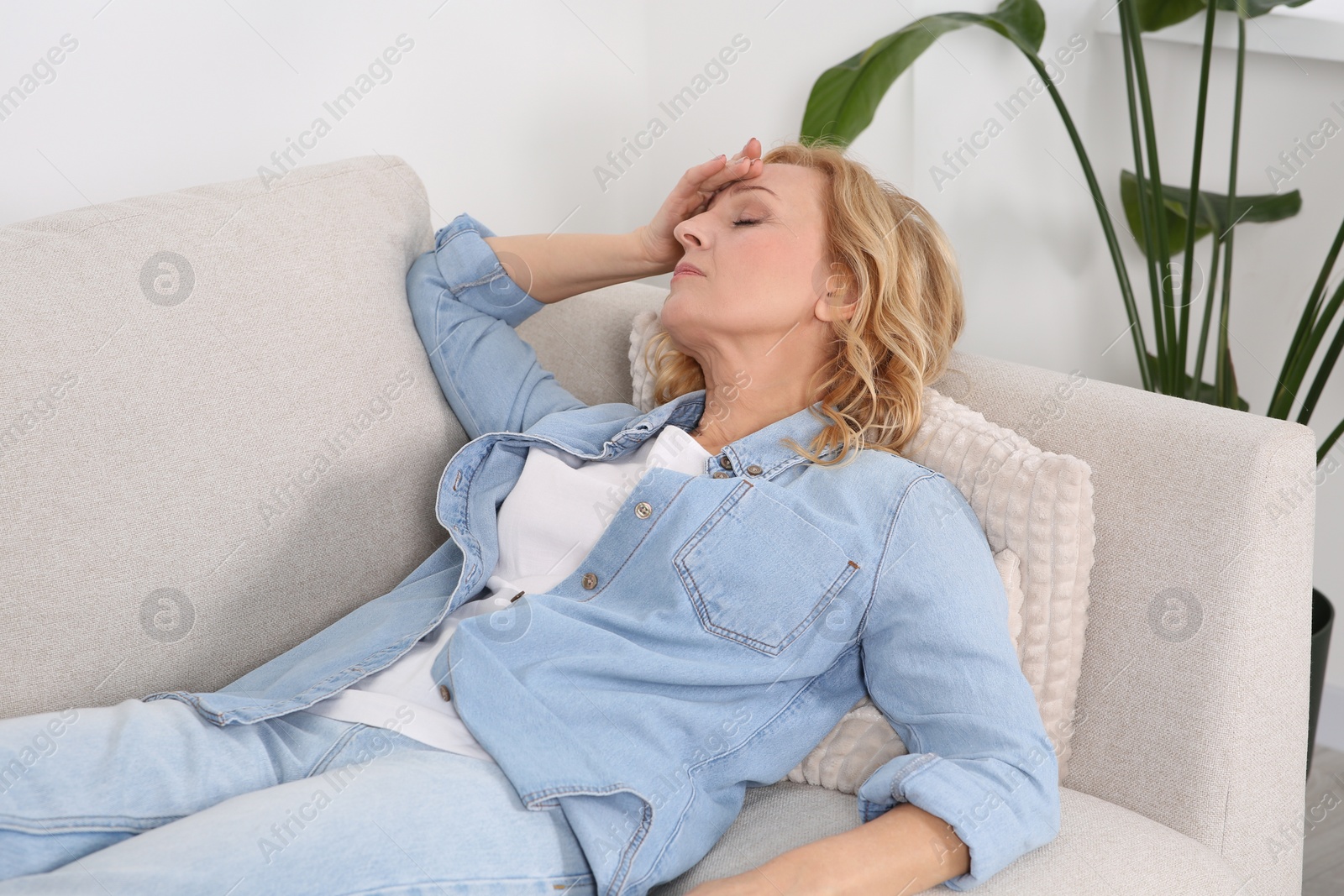 Photo of Woman suffering from headache on sofa at home. Hormonal disorders