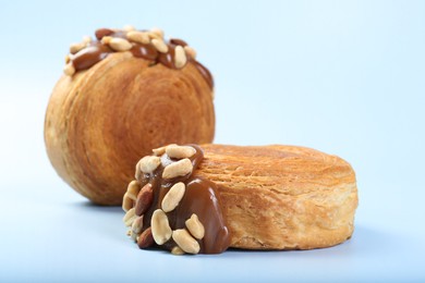 Supreme croissants with chocolate paste and nuts on light blue background, closeup. Tasty puff pastry