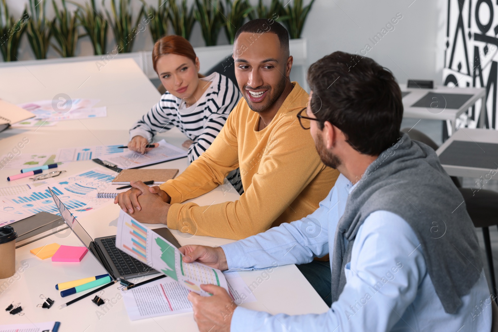 Photo of Team of employees working together at table in office. Startup project