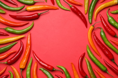 Photo of Frame made with different chili peppers on red background, flat lay. Space for text