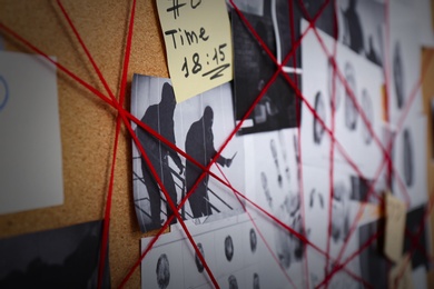 Detective board with crime scene photos, fingerprints and red threads, closeup