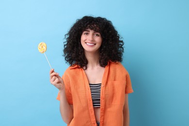 Beautiful woman with lollipop on light blue background