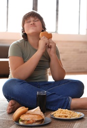 Emotional overweight boy with fast food at home