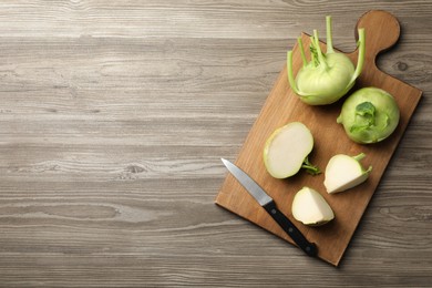 Photo of Whole and cut kohlrabi plants on wooden table, top view. Space for text