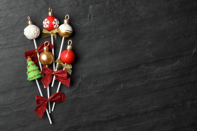 Photo of Delicious Christmas themed cake pops on black table, flat lay. Space for text