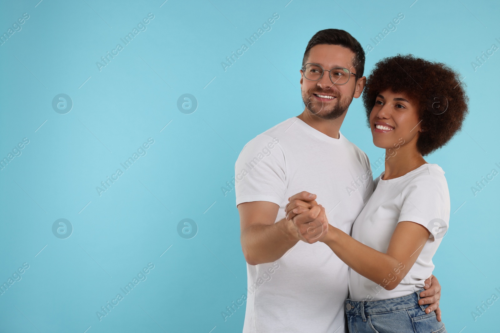 Photo of International dating. Happy couple dancing on light blue background, space for text