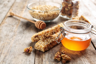 Photo of Homemade grain cereal bars and honey on wooden table. Healthy snack