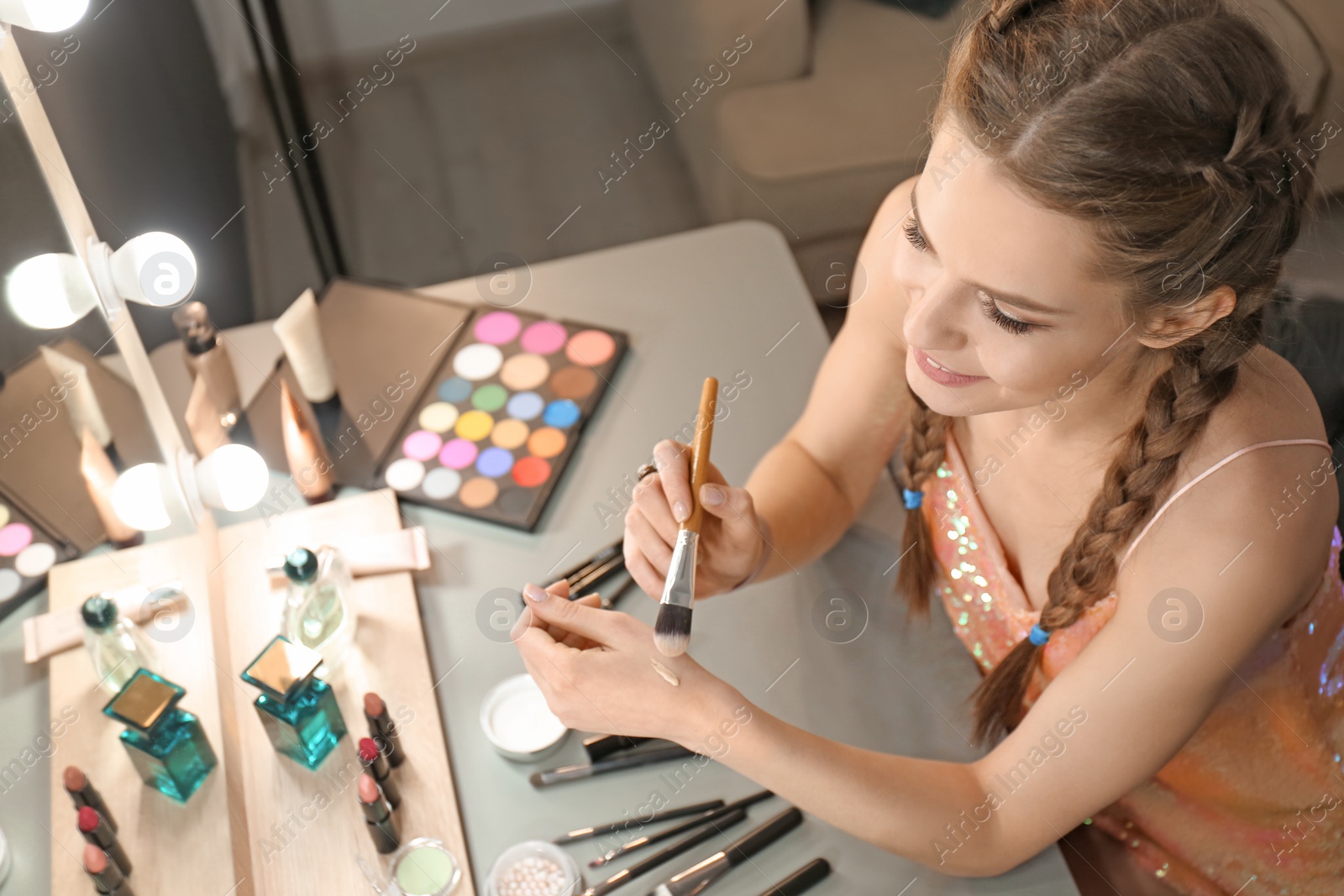 Photo of Portrait of beautiful woman applying makeup indoors