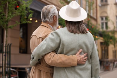 Affectionate senior couple walking outdoors, back view