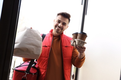 Photo of Portrait of courier with order at open door. Food delivery service