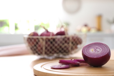 Photo of Cut red onion on wooden table in kitchen