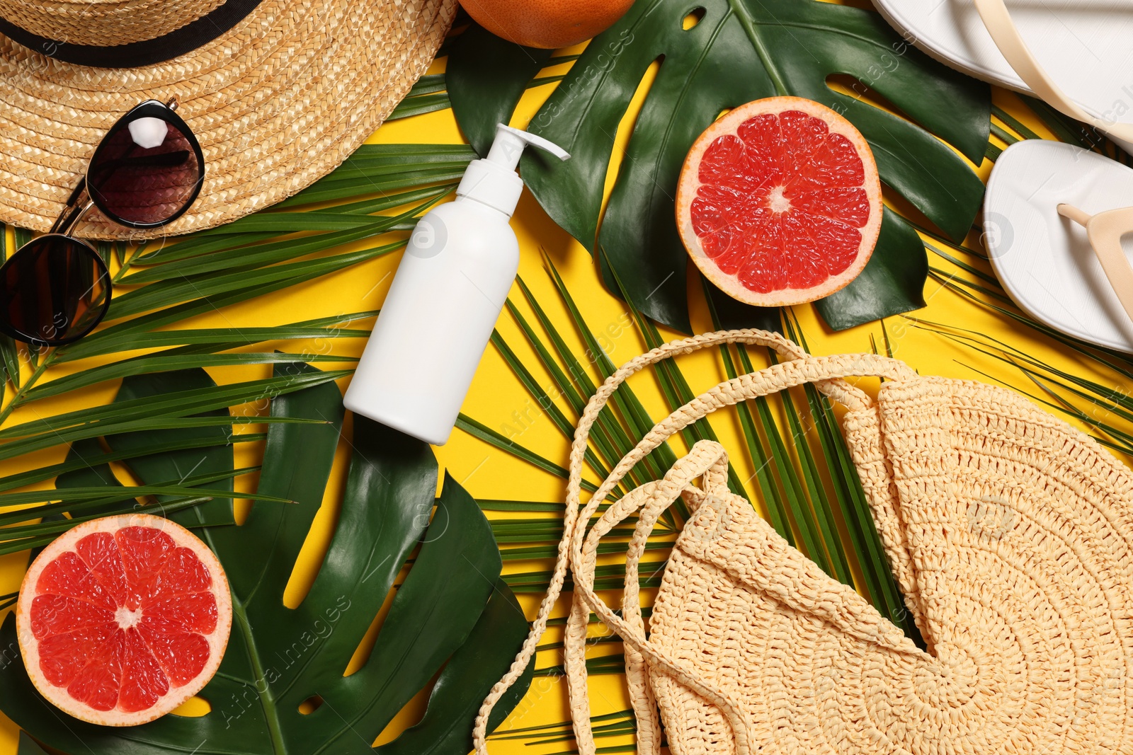 Photo of Flat lay composition with beach bag and green leaves on orange background