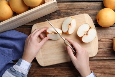 Photo of Woman cutting apple pear at wooden table, top view