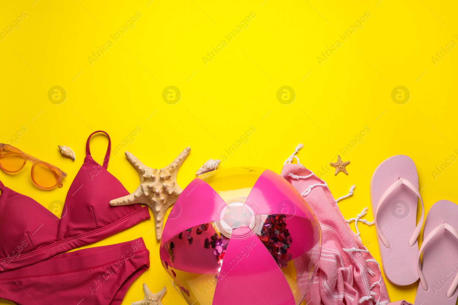 Photo of Flat lay composition with ball and beach objects on yellow background, space for text