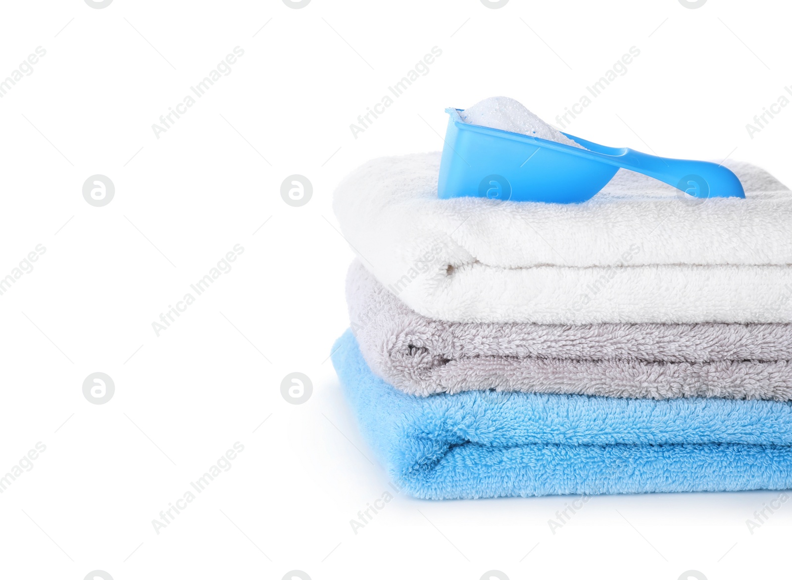 Photo of Laundry detergent in plastic measuring scoop and towels on white background