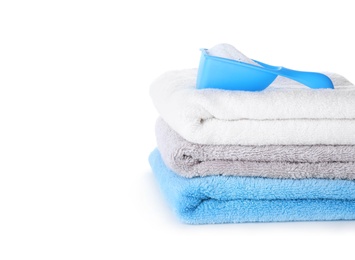 Photo of Laundry detergent in plastic measuring scoop and towels on white background