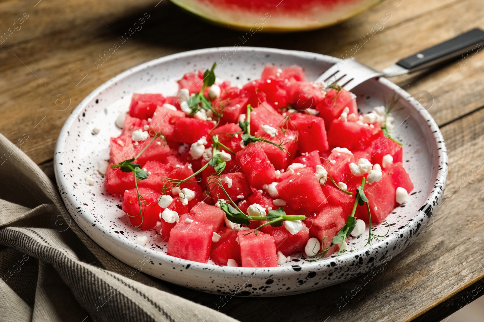 Photo of Delicious salad with watermelon served on wooden table, closeup