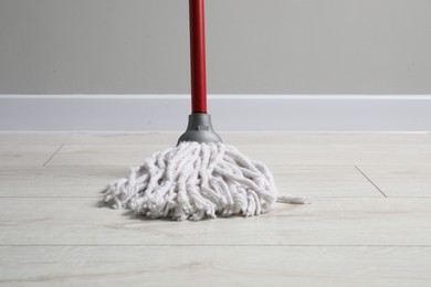 Cleaning dirty wooden floor with mop indoors