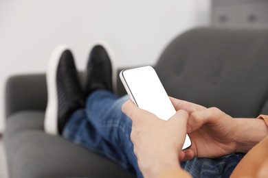 Photo of Man lying on grey sofa with smartphone, closeup. Space for text