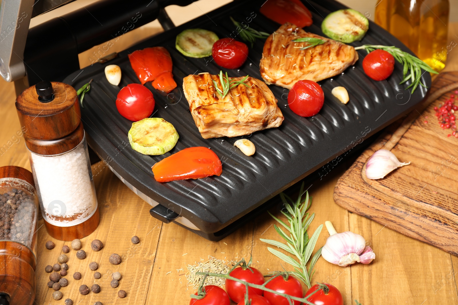 Photo of Electric grill with different products on wooden table