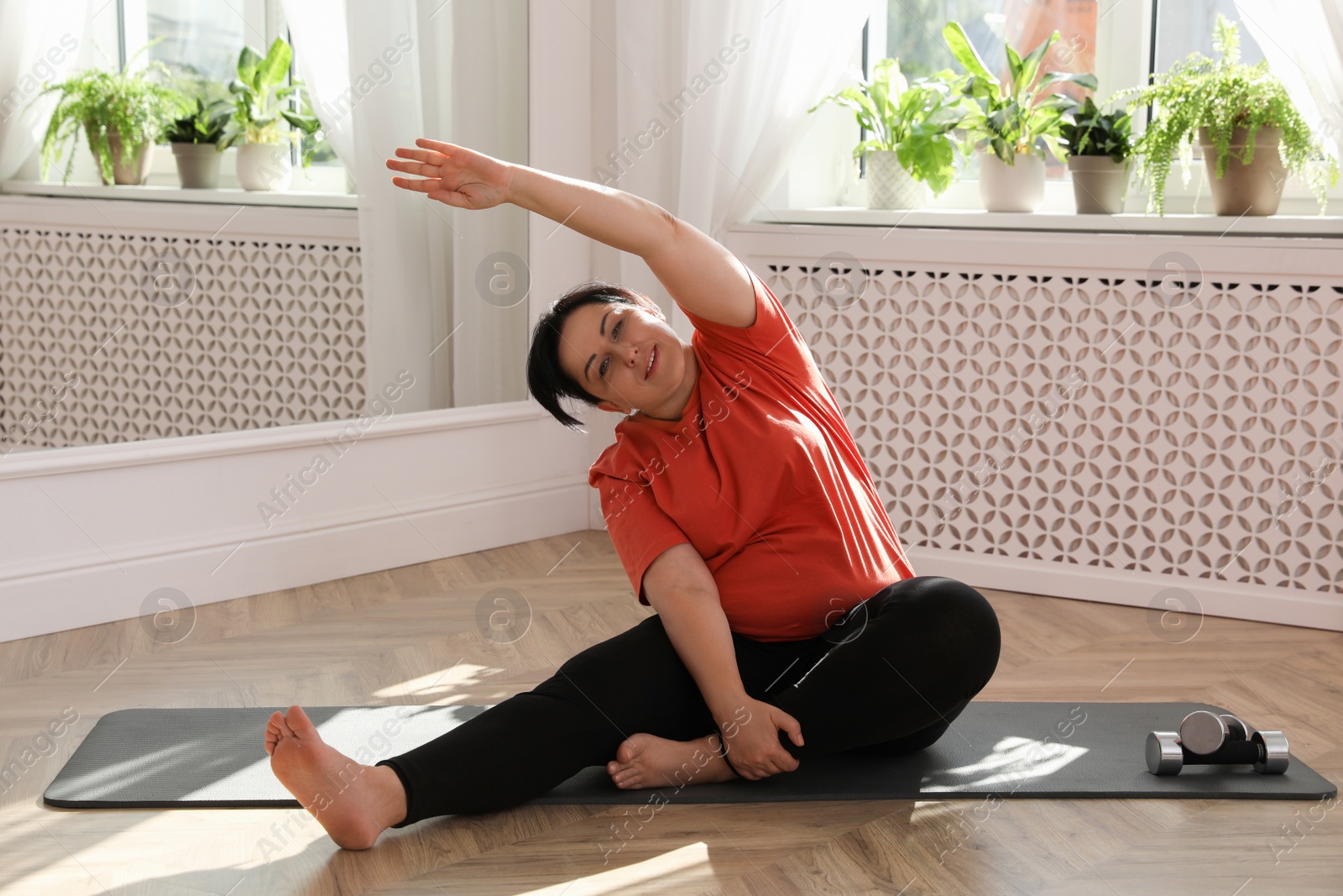 Photo of Overweight mature woman stretching on floor at home