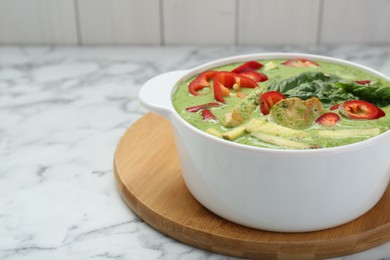 Photo of Saucepan with delicious green curry chicken soup on white marble table. Space for text
