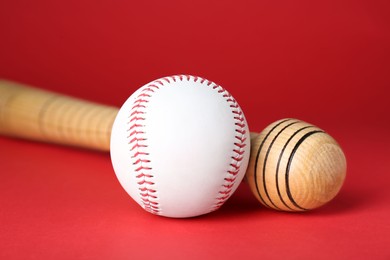 Photo of Wooden baseball bat and ball on red background, closeup. Sports equipment