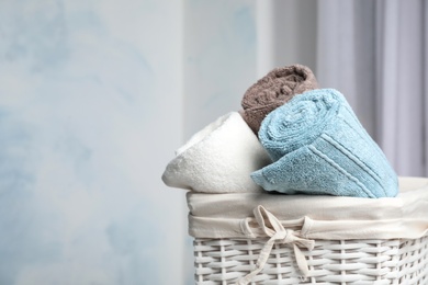 Basket with soft bath towels against blurred background. Space for text