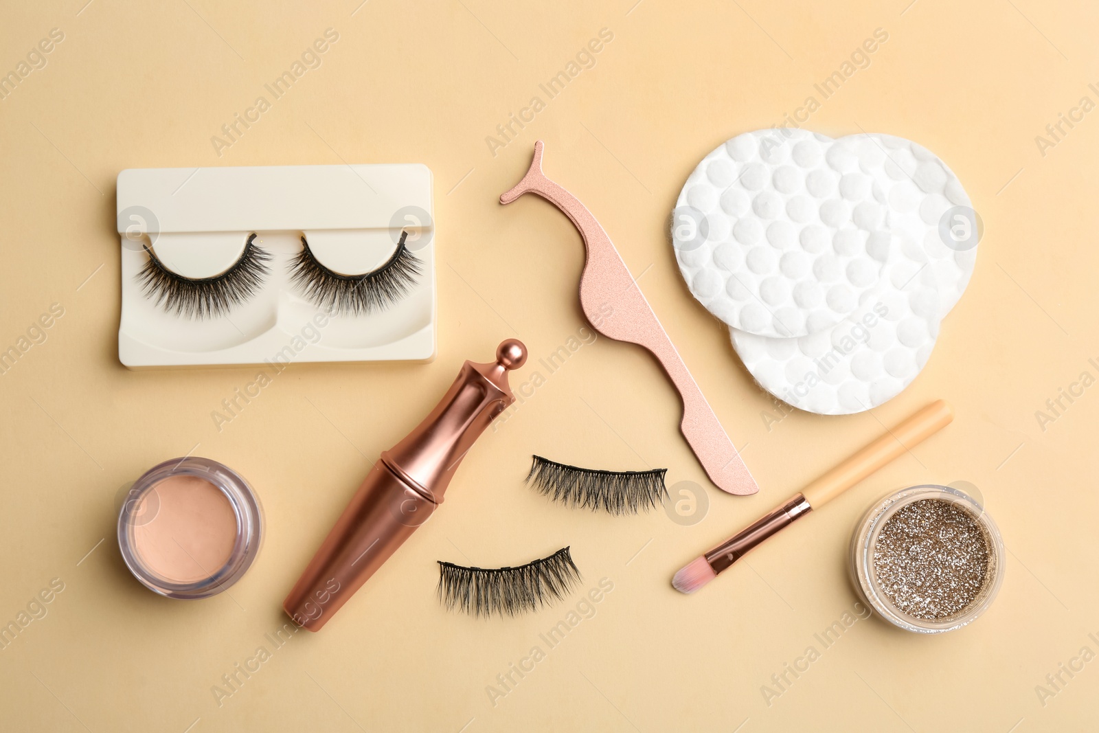 Photo of Flat lay composition with magnetic eyelashes and accessories on beige background