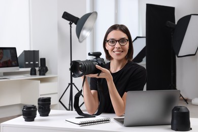 Young professional photographer with camera in modern photo studio