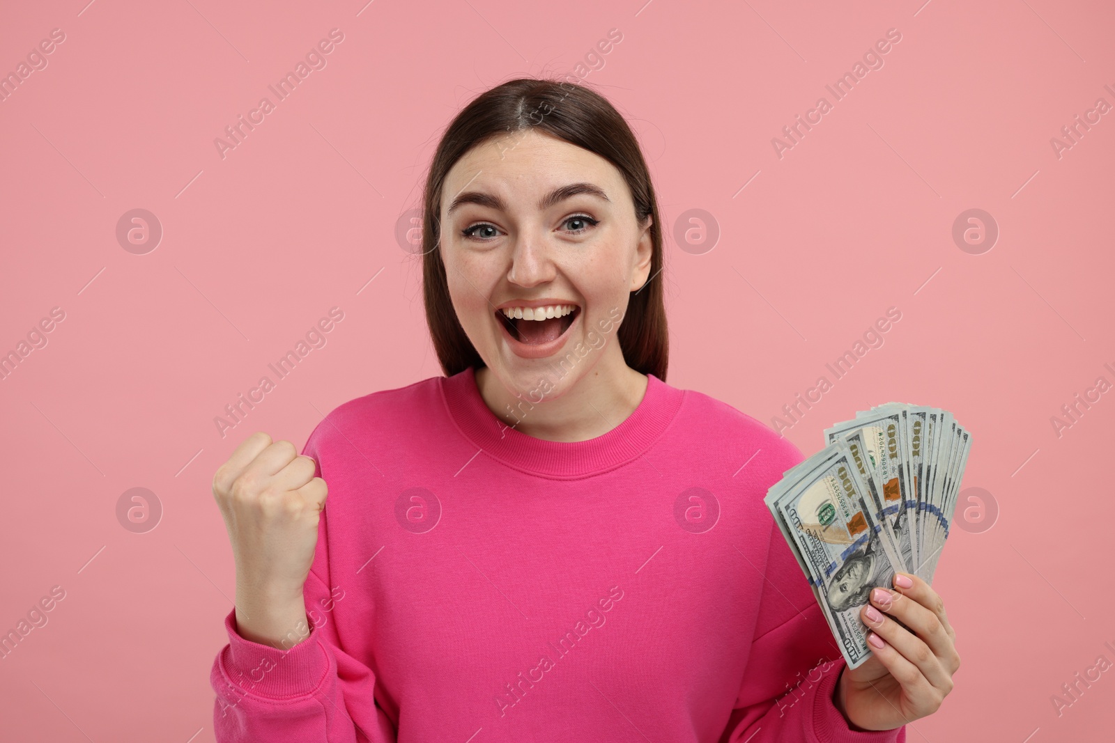 Photo of Happy woman with dollar banknotes on pink background