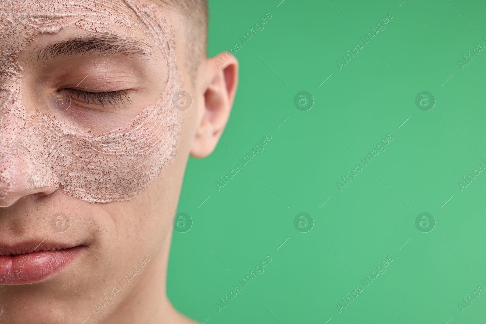 Photo of Handsome man with facial mask on his face against green background, closeup. Space for text