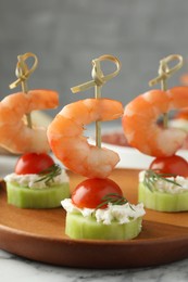 Tasty canapes with shrimps, vegetables and cream cheese on white table, closeup