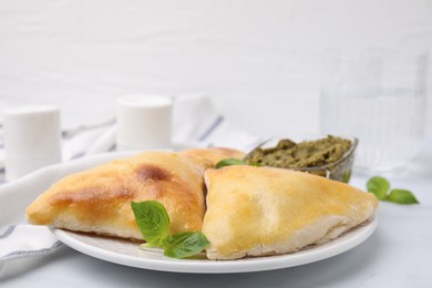 Delicious samosas with basil and pesto sauce on white table