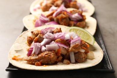Photo of Delicious tacos with vegetables, meat and lime on grey table, closeup