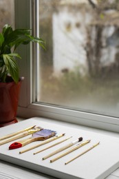 Photo of White canvas and different brushes on windowsill
