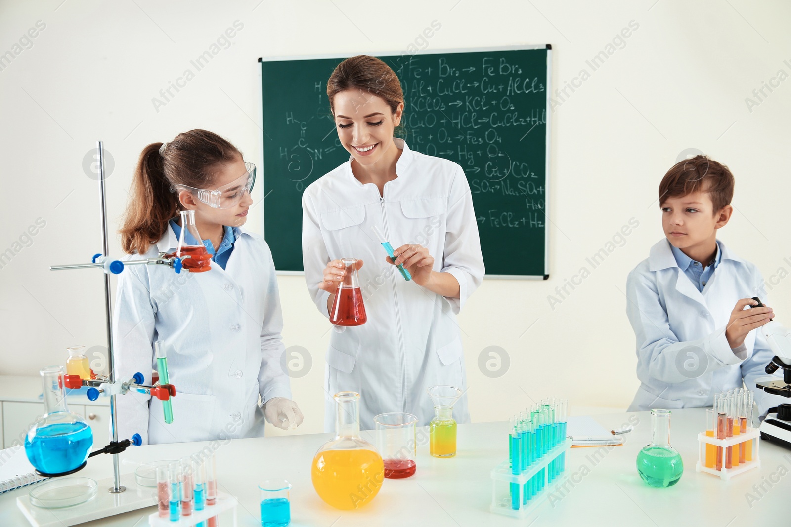 Photo of Teacher with pupils making experiment in chemistry class