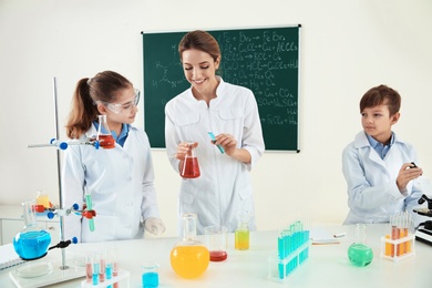 Photo of Teacher with pupils making experiment in chemistry class