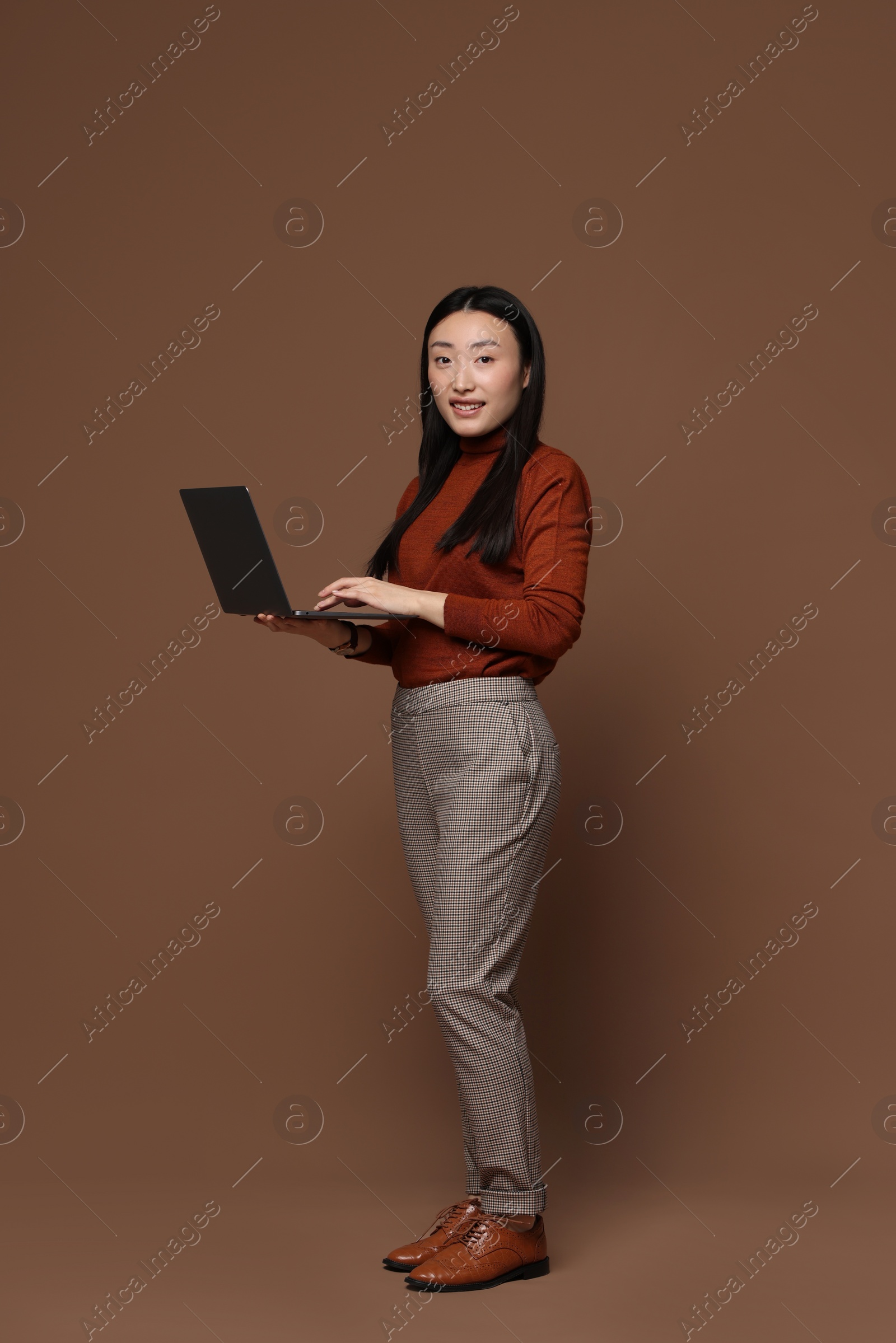 Photo of Full length portrait of smiling woman with laptop on brown background