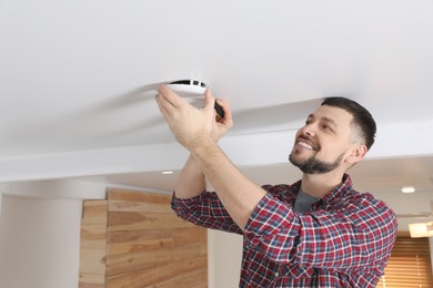 Photo of Man with screwdriver repairing ceiling lamp indoors. Space for text
