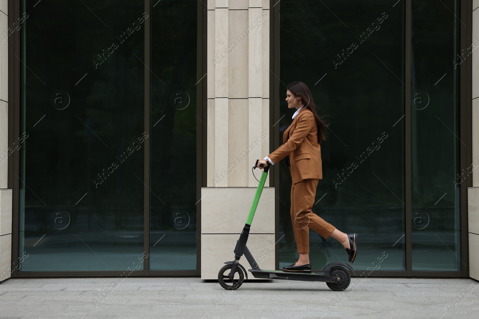 Photo of Businesswoman riding electric kick scooter on city street